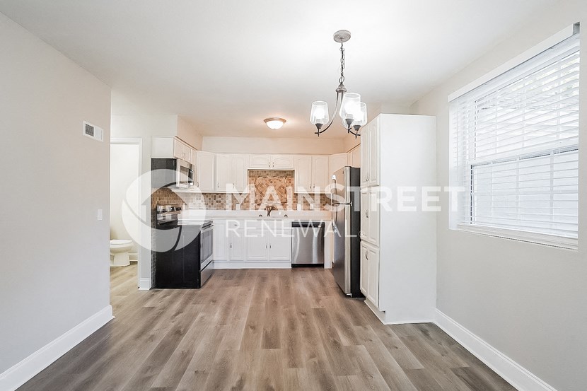 a renovated kitchen with white cabinets and a large window