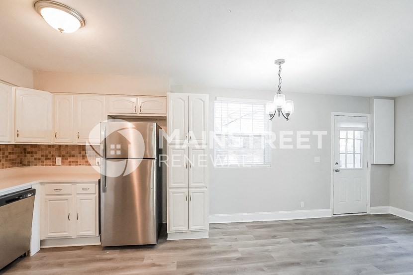 a kitchen with white cabinets and a stainless steel refrigerator