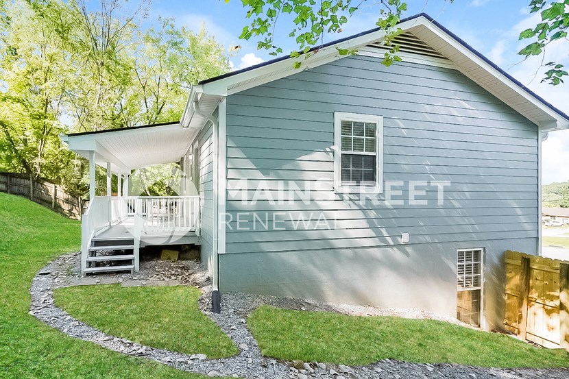a small blue house with a white deck and a porch