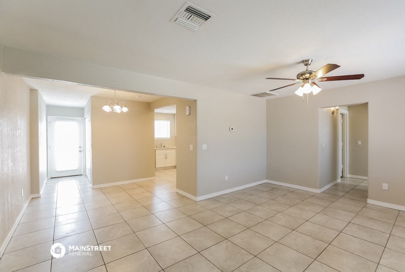 a spacious living room with tile flooring and a ceiling fan