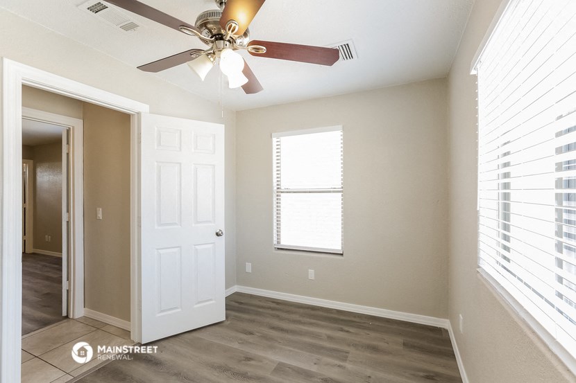 an empty room with a ceiling fan and a door