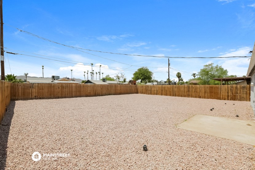 an empty yard with a wooden fence and a blue sky