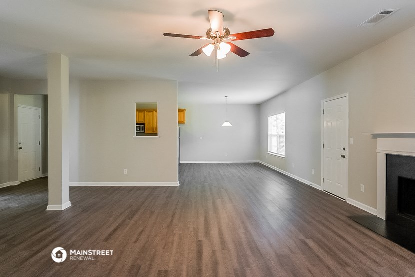an empty living room with a ceiling fan and a fireplace