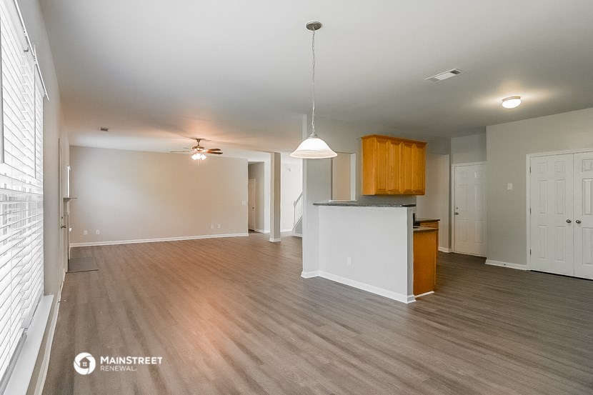 an empty living room and kitchen with wood flooring