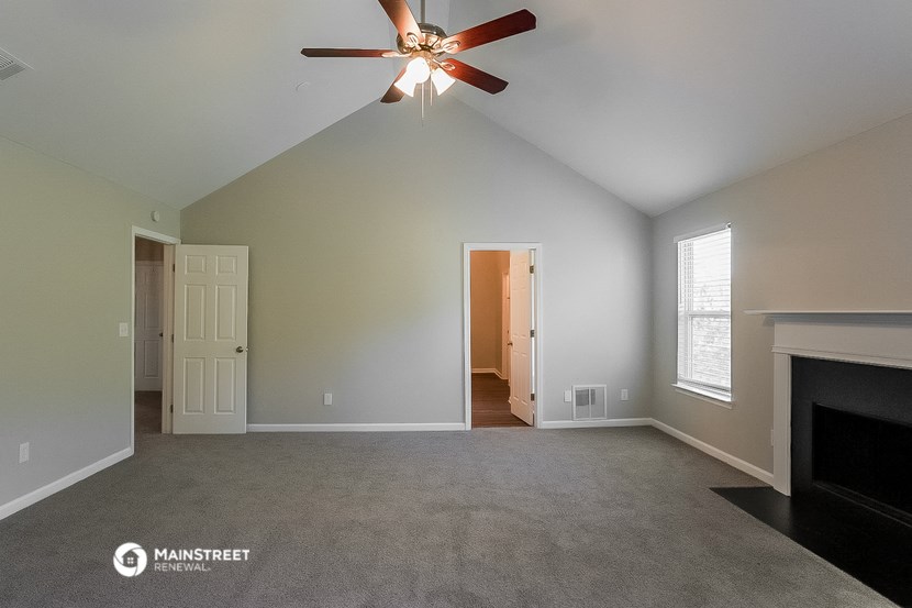 the living room of an empty house with a ceiling fan