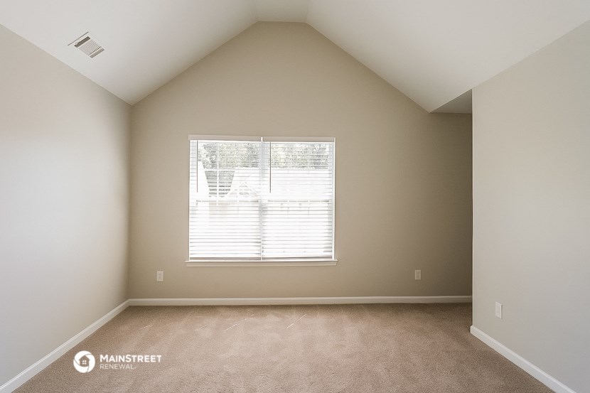 an empty bedroom with a window and carpeting