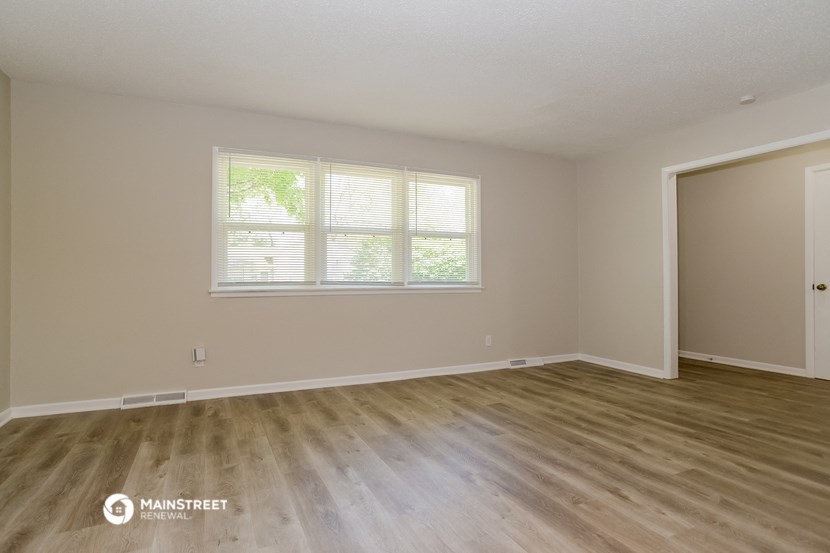 the spacious living room with wood flooring and a large window