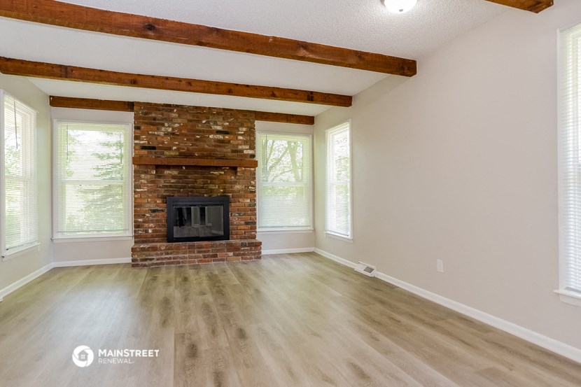 the living room with a fireplace and wooden floors