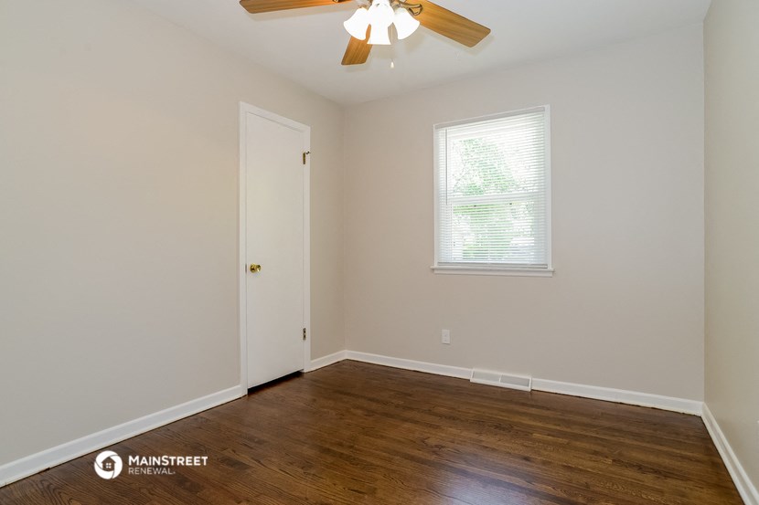 a bedroom with wood floors and a ceiling fan