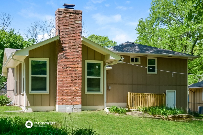 a brown house with a brick chimney and a yard