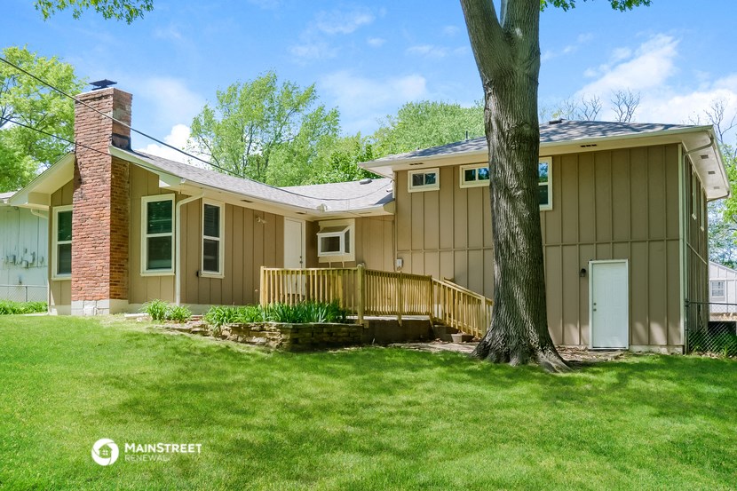 a yellow house with a deck and a tree