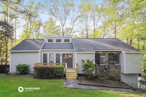 a white house with a gray roof and a lawn and trees