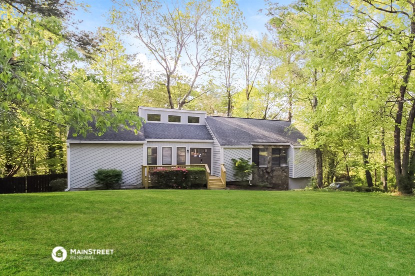 a white house in the woods with a large yard
