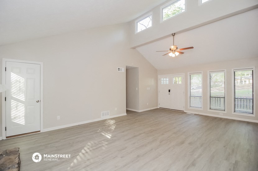 an empty living room with white walls and a ceiling fan