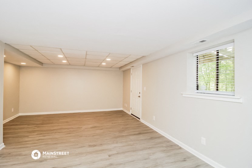 the spacious living room with wood flooring and a window