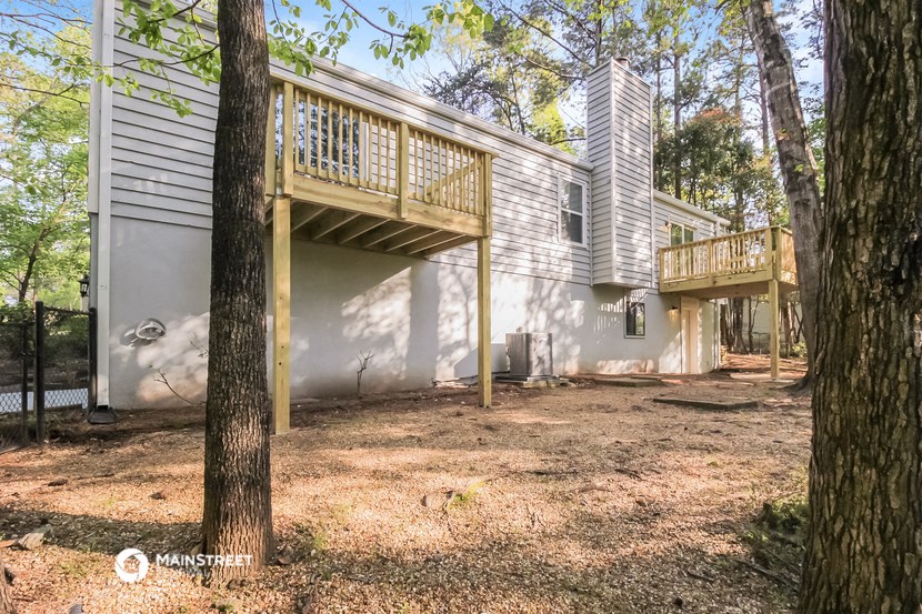 a white house with a balcony and a deck in the woods