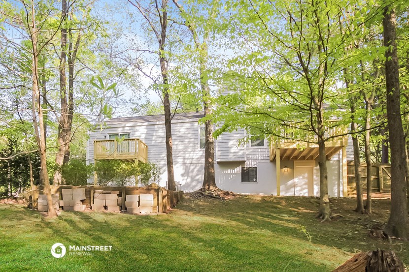 the exterior of a white house in the woods with trees