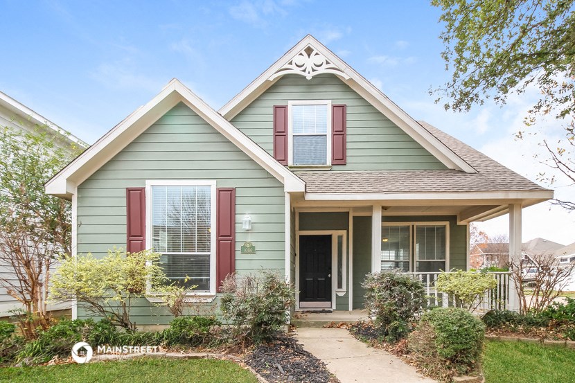 a green house with red shutters and a sidewalk in front of it