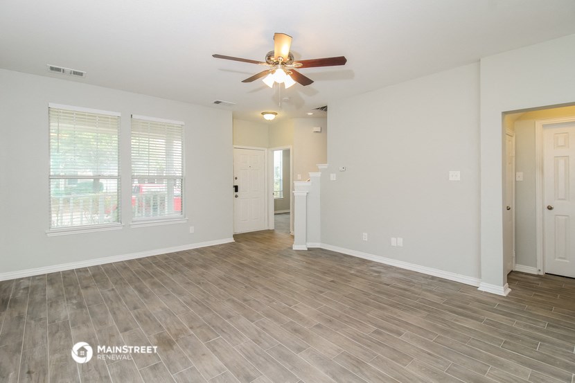 the living room of an empty house with a ceiling fan
