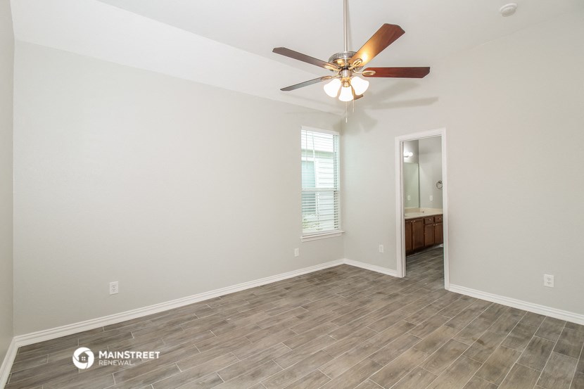 the spacious living room with wood flooring and a ceiling fan