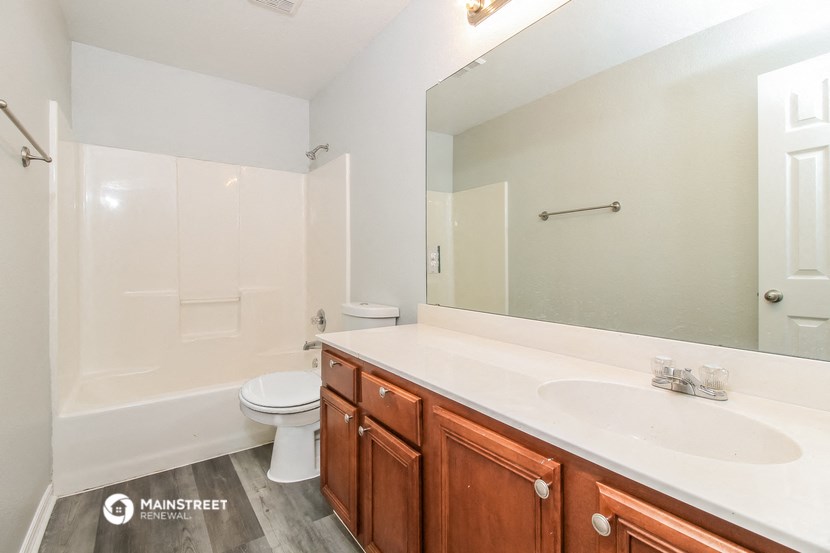 a bathroom with a large mirror and a sink and a toilet
