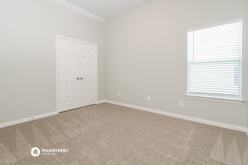 a bedroom with a white door and a carpeted floor