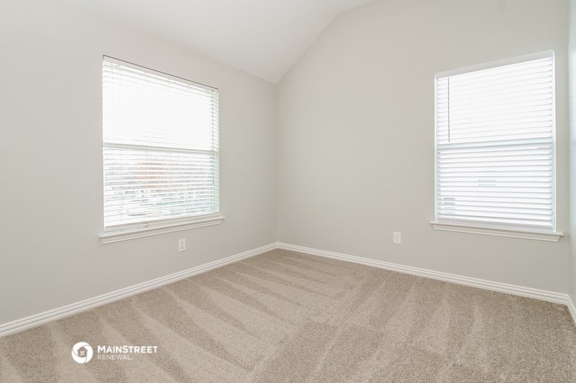 the upstairs bedroom with carpet and two windows