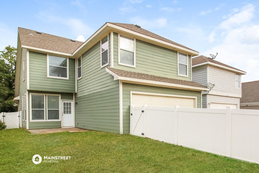 a green house with a white fence in front of it