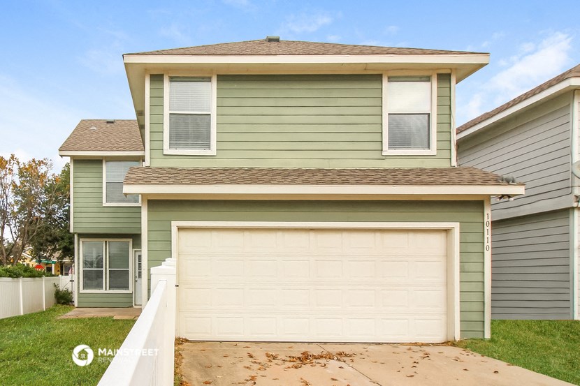 a green house with a white garage door