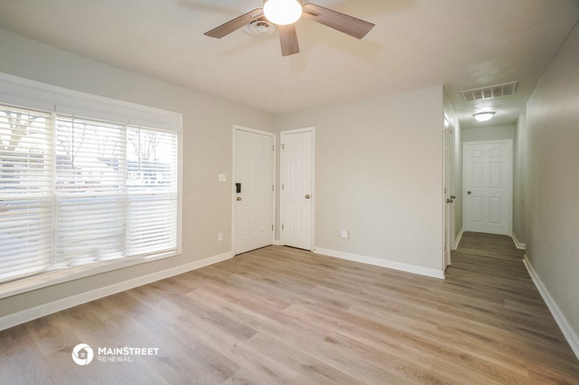an empty living room with wood floors and a ceiling fan