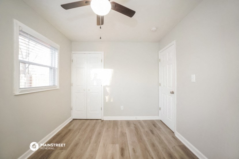 an empty room with a ceiling fan and a window