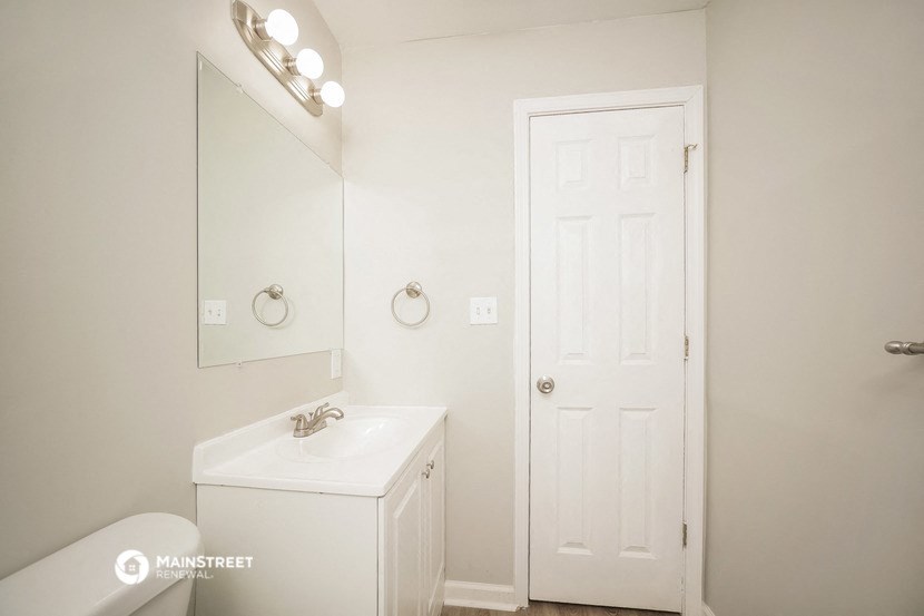 a bathroom with a sink and a mirror and a white door