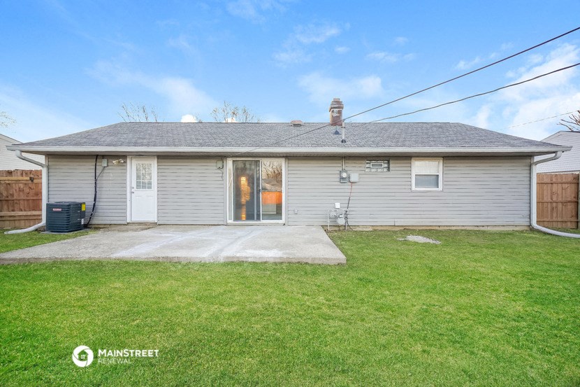 a small white house with a yard and a driveway