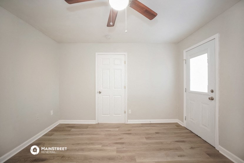 the living room of an empty house with a ceiling fan