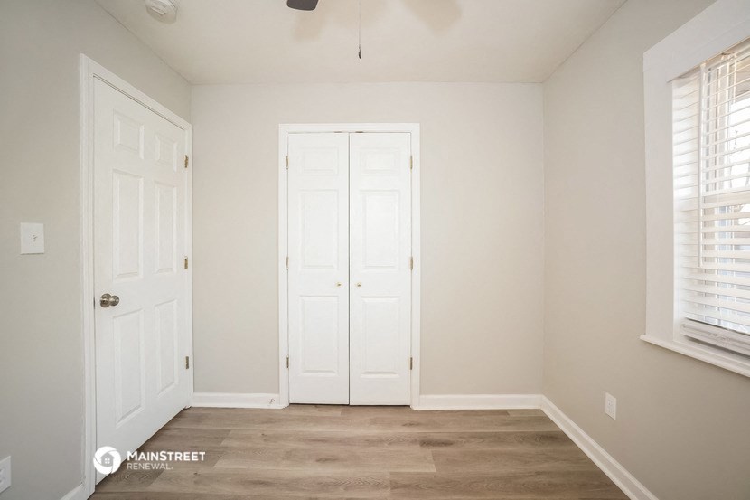 a bedroom with two closets and a door and a window