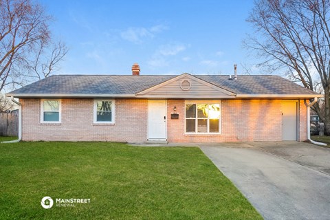 the front of a brick house with a driveway and grass