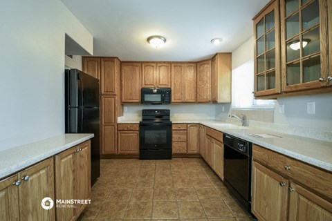 an empty kitchen with wooden cabinets and black appliances