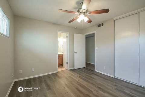 an empty living room with a ceiling fan and a door to a bathroom