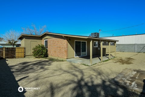 a small tan brick house with a driveway and a gate