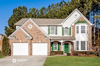 a brick house with green shutters and white garage doors
