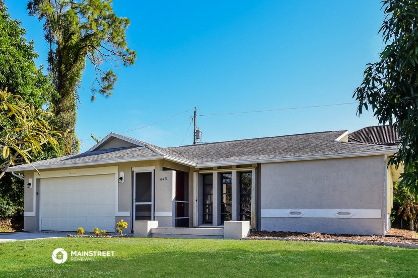 a white house with a lawn and a tree