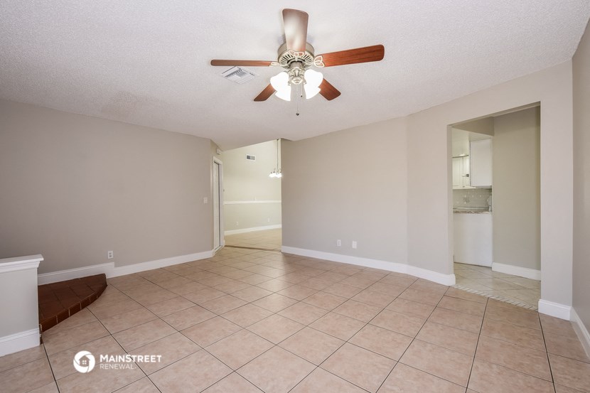 an empty living room with a ceiling fan and a tiled floor