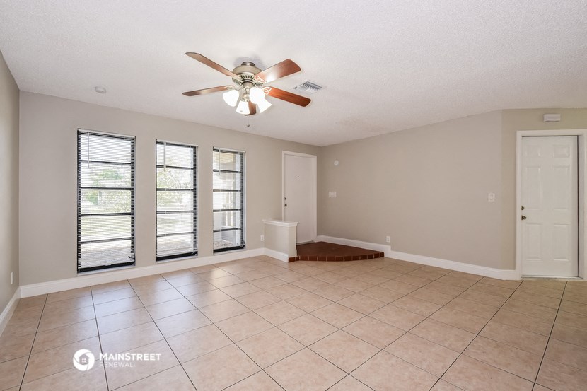 an empty living room with a ceiling fan and a tiled floor