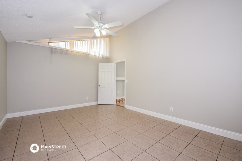 an empty living room with a ceiling fan and a tile floor