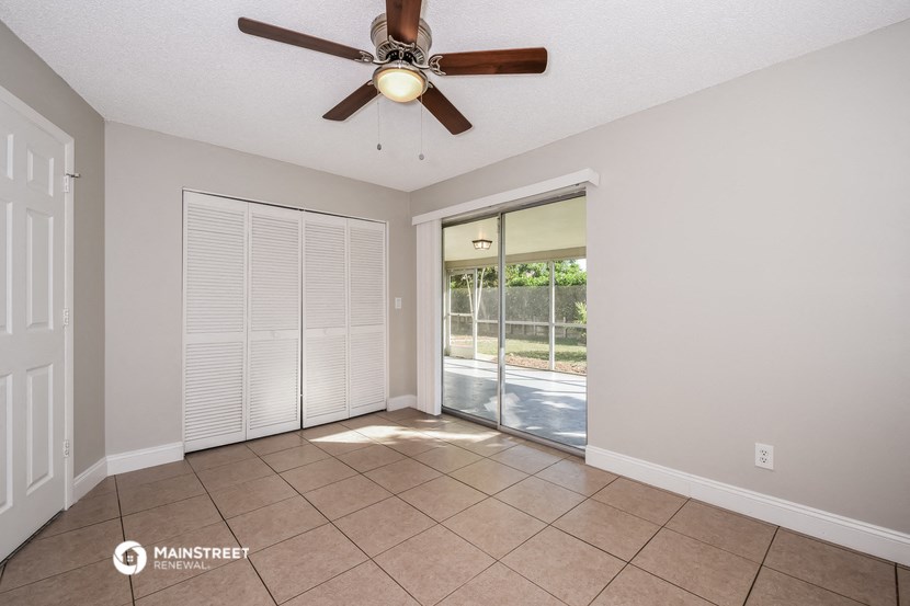 an empty living room with a ceiling fan and a sliding glass door