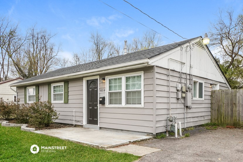 a small white house with a driveway and a black door