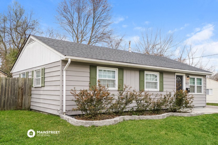 a small white house with green shutters and a lawn