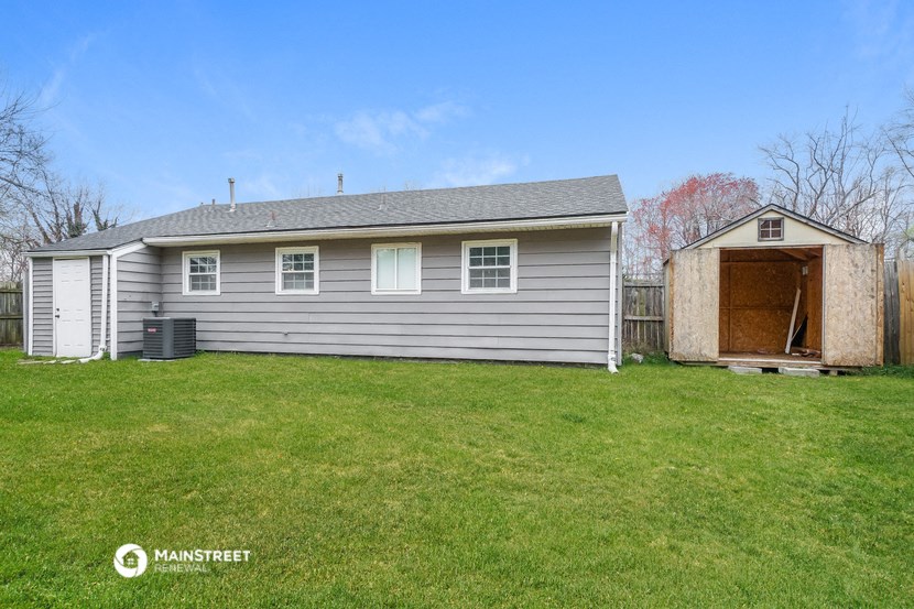 a small gray house with a garage and a yard