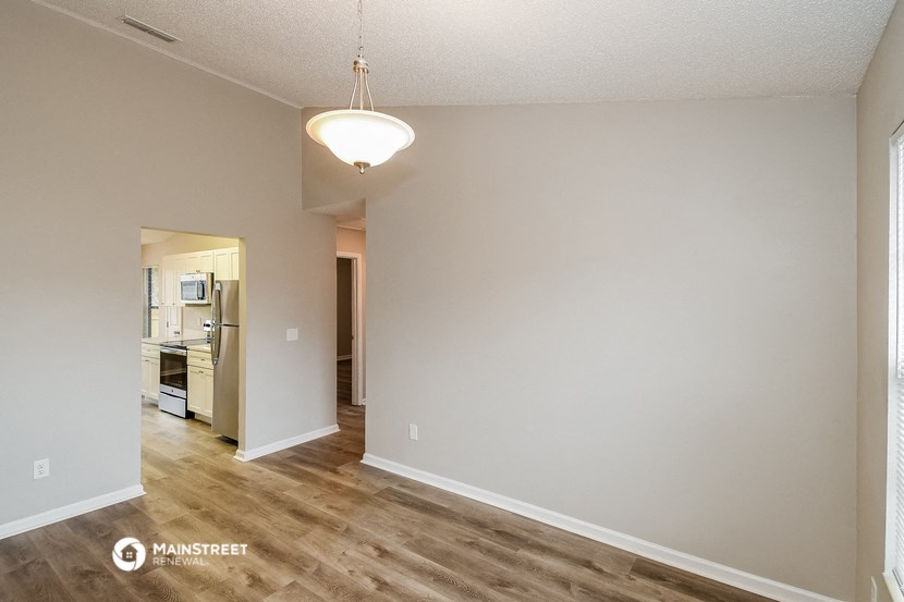 a spacious living room with hardwood flooring and a kitchen