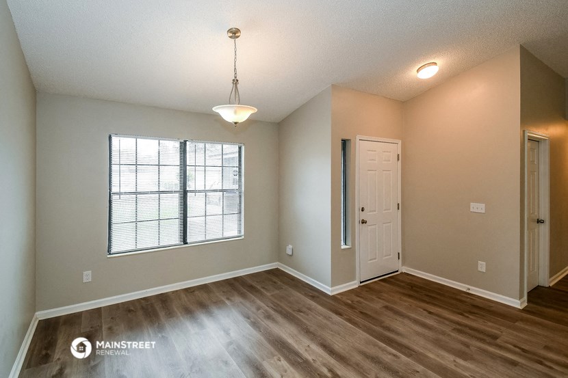 an empty living room with a white door and a window
